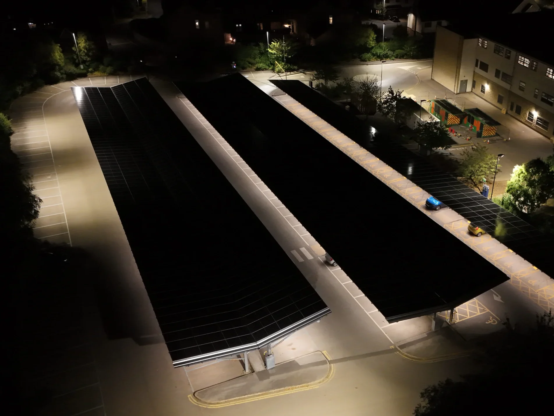 Wharfedale-Hospital-cropped Night drone aerial of Wharfedale Hospital car park illuminated beneath Bluetop Solar OPTI solar canopies generating clean energy